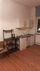 a kitchen with white cabinets and a wooden floor at Double Room with a Kitchen and a Shared Bathroom in Bremen