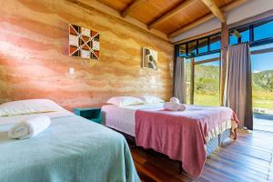 a bedroom with two beds and a large window at Villa Taipas - Chalé Ariê in Cavalcante