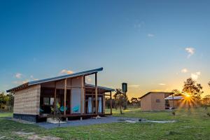 una casa en un campo con la puesta de sol en el fondo en Villa Taipas - Chalé Ariê, en Cavalcante