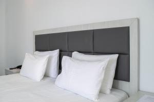 a bed with white pillows and a gray headboard at Giannoulaki Resort in Glastros