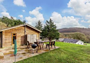 uma cabina de madeira com uma mesa e cadeiras e um grelhador em Meadow Lodge - Cornwall em Cardinham
