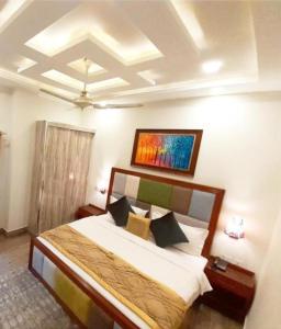 1 dormitorio con 1 cama y una pintura en la pared en Hayyat Luxury Suites, en Lahore