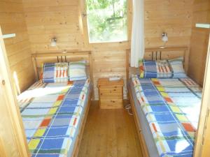 2 łóżka w niewielkim pokoju z drewnianymi ścianami w obiekcie U M&M w Łagowie