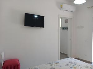 een kamer met een tv aan een witte muur bij Da Raff house in Ischia