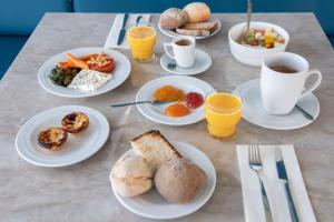 a table with plates of breakfast foods and cups of coffee at Sines Sea View Business & Leisure Hotel in Sines