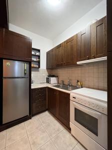 a kitchen with wooden cabinets and a stainless steel refrigerator at BLUE DREAM in Koropi