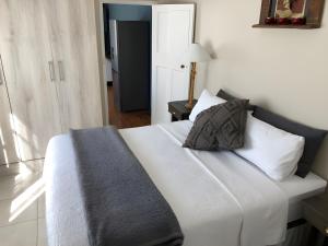 a bedroom with a bed with white sheets and pillows at Rustic Inn in Swakopmund