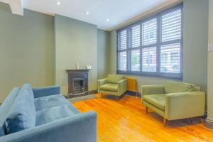 a living room with a couch and two chairs and a fireplace at Inviting 4BD with Private Patio - Bethnal Green in London