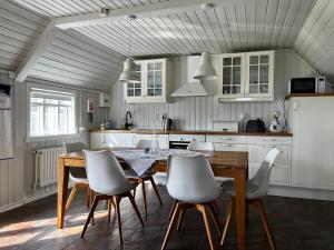 cocina con mesa de madera y sillas blancas en Jóhönnu Hús, en Hella