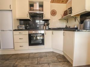 a kitchen with white cabinets and an oven at Doormouse Lodge in Carnforth