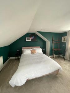 a bedroom with a large white bed with a green wall at Stylish & Peaceful 2BD Flat - Near Wimbledon in London
