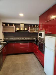 una cocina roja con electrodomésticos blancos y armarios rojos en Casa Auga Boa, en Cangas de Morrazo