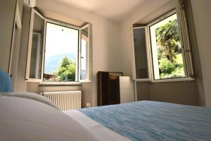 Schlafzimmer mit zwei großen Fenstern und einem Bett in der Unterkunft Appartamento Belle Epoque vista lago in Onno