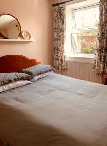 um quarto com uma cama com um espelho e uma janela em Comfy 3BD Home with Patio in Peaceful Ilminster em Ilminster