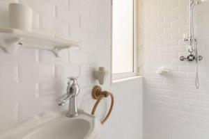La salle de bains blanche est pourvue d'un lavabo et d'une douche. dans l'établissement Classy 2BR in Principe Real w/ Heating, à Lisbonne