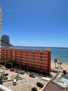 duży czerwony budynek obok plaży w obiekcie Playa de Oro con Parking w mieście Calpe