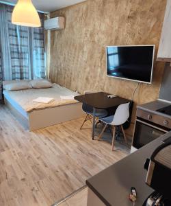 um pequeno quarto com uma cama, uma mesa e uma televisão em Colonel apartment 963 em Sófia