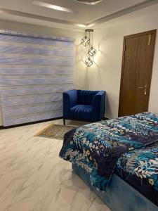 a bedroom with a bed and a blue chair at The Family Den in Rawalpindi
