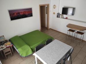 een kamer met een groen bed en een tafel bij Appartamento Wilma in Spormaggiore