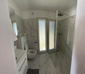 a white bathroom with a toilet and a sink at Lipno View Jenišov in Jenišov