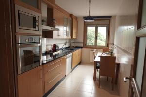 a kitchen with wooden cabinets and a table in it at Piso Alerín in Silleda