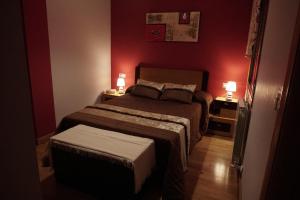 a bedroom with a bed with red walls and two lamps at Piso Alerín in Silleda