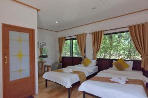 a bedroom with three beds and a window at Chomduen Phu Kao Resort in Non Sang