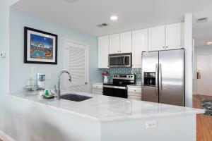 a white kitchen with a stainless steel refrigerator at 13108 Pelican Watch Villa in Seabrook Island +16 photos