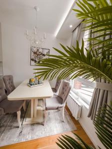 a dining room with a white table and a plant at Fontana apartmani FREE parking in Tuzla