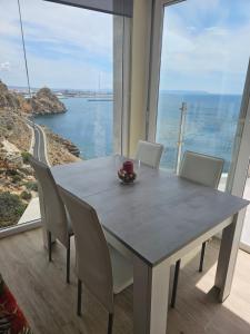 a dining room table with chairs and a view of the ocean at Casa del Mar in Almería