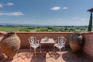 eine Terrasse mit Stühlen, einem Tisch und zwei großen Vasen in der Unterkunft Locanda Poggioleone in Castiglione del Lago