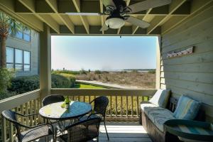 a screened porch with a table and chairs and a ceiling fan at 1385 Pelican Watch Villa in Seabrook Island