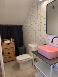 La salle de bains est pourvue de toilettes et d'une boîte rose sur une table. dans l'établissement Le trois nourrices, à Narbonne