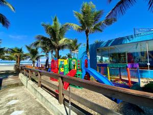un colorido parque infantil en una playa con palmeras en Residencial João Orisaka, en Samaritá