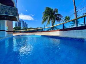 Una piscina azul con una palmera al fondo. en Residencial João Orisaka, en Samaritá