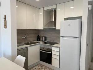 a kitchen with white cabinets and a white refrigerator at Montiro in L'Escala
