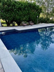 una piscina con 2 sillas y un reflejo en el agua en The Farmhouse at Glenwood Retreats, 