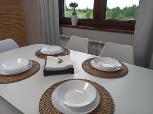 d'une table blanche avec des plaques et des serviettes blanches dans l'établissement Apartament GRAY CRANE, à Giżycko