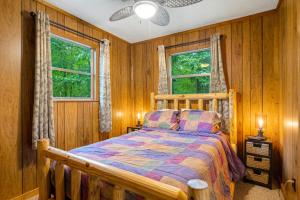 a bedroom with a bed with wooden walls and windows at Artisan Hideaway in Helen