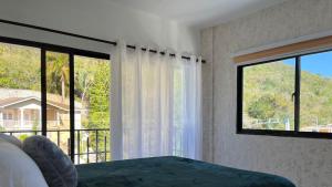 a bedroom with two windows and a bed and a balcony at Loma Alta Hotel Boutique in Polo