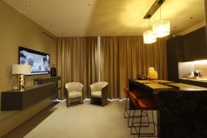 um quarto de hotel com um bar com cadeiras e uma televisão em Giargeri Home em Misterbianco