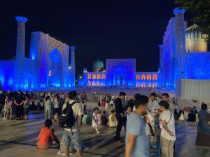 un grupo de personas de pie en frente de un edificio con luces azules en MehmonServis1, en Samarkand