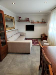 a living room with a white couch and a television at Casa Auga Boa in Cangas de Morrazo