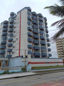 un gran edificio de apartamentos con una palmera frente a él en Ótimo Apartamento Frente ao Mar em Mongaguá, en Mongaguá
