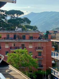 a red brick building with a mountain in the background at Gassa d'Amante Appartamento in Rapallo