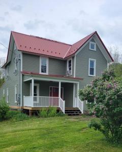 a gray house with a red roof and a yard at FLX 1890's Farmhouse in Hector