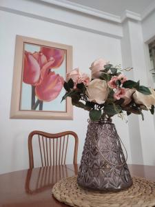 een vaas gevuld met roze rozen zittend op een tafel bij Piso Sol in Laxe