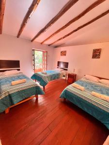 two beds in a room with wooden floors at Posada Del Valle Lodge in Urubamba
