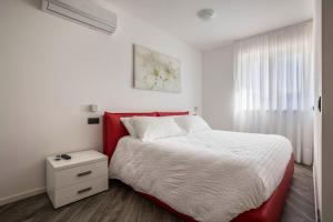 Un dormitorio con una cama roja y blanca y una ventana en Appartamenti Gaggiolo 1, en Dro
