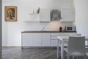 una cocina con armarios blancos y una mesa con sillas. en Appartamenti Gaggiolo 1, en Dro